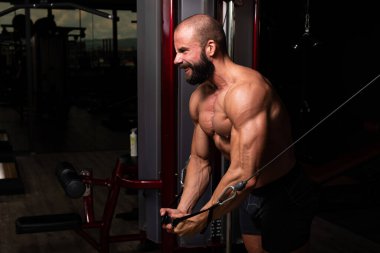 Kas geliştirme vücut geliştiricisi spor salonunda kablolu TV ile göğüs egzersizi yapıyor.