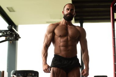 İyi eğitilmiş vücudunu gösteren genç bir adamın portresi - kaslı atletik vücut geliştirici spor sonrası vücut geliştirme modelliği pozu