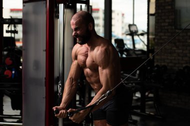 Kas geliştirme vücut geliştiricisi spor salonunda kablolu TV ile göğüs egzersizi yapıyor.