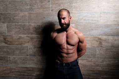 İyi eğitilmiş vücudunu gösteren genç bir adamın portresi mavi kot giyerken - kaslı atletik vücut geliştirici spor modeli pozu duvarın yanındaki duvarda egzersiz yaptıktan sonra - metinleriniz için bir yer