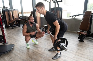 Kişisel Eğitmen Genç Adam 'a Salonda Halterle Nasıl Antrenman Yapılacağını Gösteriyor