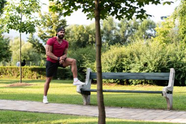 Açık havada koştuktan sonra Park Bench 'te dinlenen mutlu bir gencin portresi.