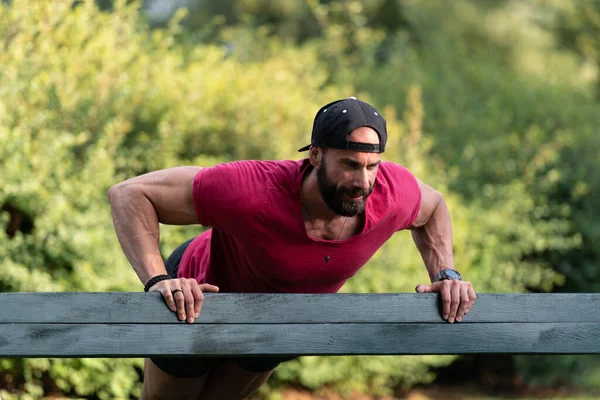 Knappe Jongeman Een Rood Shirt Pushups Een Bankje Het Park — Stockfoto