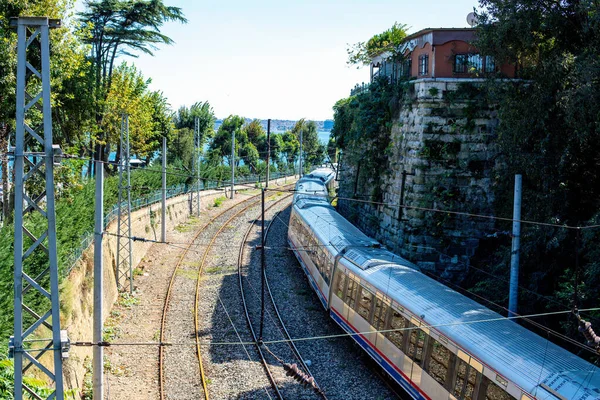 Die Eisenbahn wendet sich dem Meer zu. Zug auf der Bahn mit Meerblick. ein Zug zwischen grünen Bäumen und Steinmauer. — Stockfoto