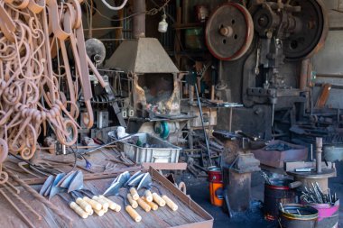 Metal işleme atölyesi. Soyu tükenmiş Forge. Demirci işyeri. Çeşitli donanım ve demir ürünleri. Bir sürü metal ve kir..