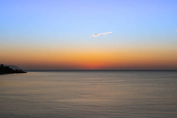 Meereshorizont bei Sonnenaufgang. Meerblick bei Sonnenuntergang. die einzige Wolke am blauen Himmel. Orangefarbener Sonnenaufgang über dem Ozean. ein heller Schein — Stockfoto