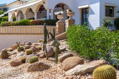 Sharm El Sheikh, Egypt - 11.04.2019: Hyatt Regency Sharm El Sheikh Resort. Decorative landscaping from Cactus garden. Different cacti on gravel and huge cobblestones around. Luxury villa with columns.