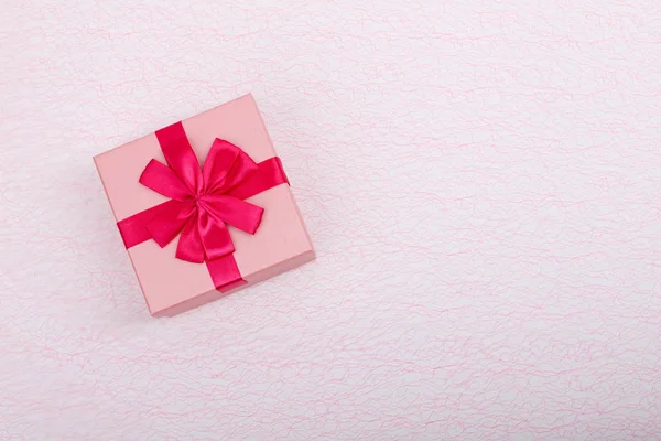 Regalo en una caja rosa sobre un fondo rosa claro con un espacio de copia. Caja de regalo con una vista superior de cinta roja. Caja de regalo simple y espacio de copia Imágenes De Stock Sin Royalties Gratis