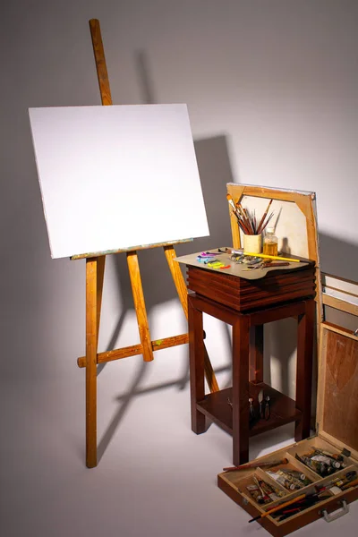 Pittura ad olio. Tela bianca su Easel. Tavolozza con vernici e pennelli. Sprema vernici ad olio su una tavolozza. Panno pulito con spazio copia. Set di pennelli in una tazza. Subframe e strumenti di disegno . — Foto Stock