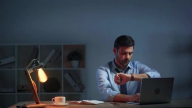 İş adamı ofisteki saate bakıyor 