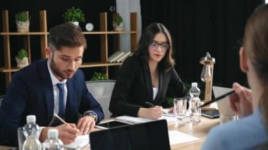 Genç iş kadını iş arkadaşlarının yanında su içiyor.