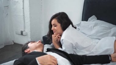 İş adamı yatakta uzanıyor ve kız arkadaşıyla konuşuyor. 