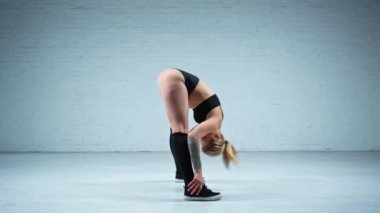 Dans stüdyosunda esneme hareketleri yapan çekici bir dansçı.