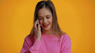 Zeki telefondan konuşan gülümseyen genç sarıda izole edilmiş.