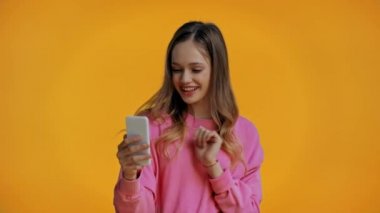 Sarı üzerine izole edilmiş görüntülü arama yapan gülümseyen genç.