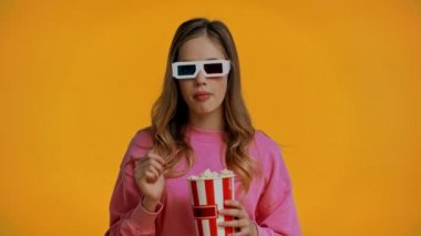 Genç kız film izliyor ve sarı üzerine izole edilmiş patlamış mısır yiyor.