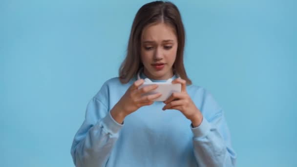 Mavi Renkte Izole Edilmiş Akıllı Telefonla Oynayan Genç — Stok video