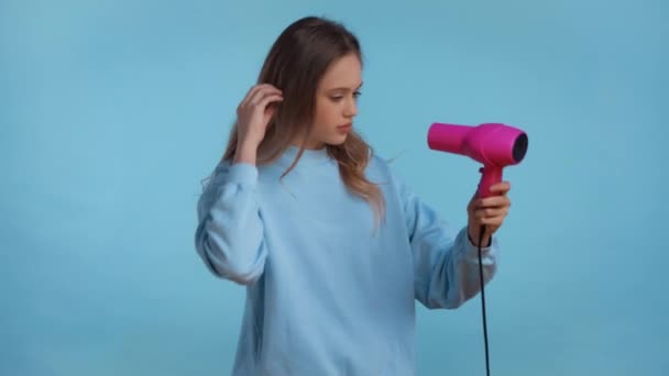 Irritated Teenager Drying Hair Isolated Blue — Stock Video
