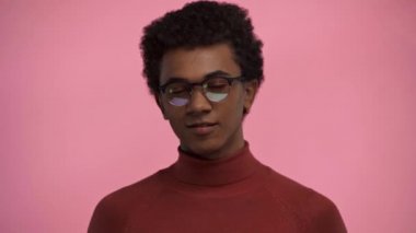 Afro-Amerikan genci, pembe üzerine izole edilmiş parmağıyla işaret ediyor.