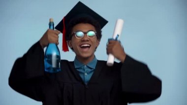 Afrika kökenli Amerikalı ergen mavi alanda izole edilmiş bir diploma tutuyor.