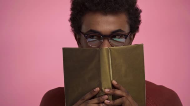 Africano Americano Adolescente Obscurecer Cara Con Libro Aislado Rosa — Vídeo de stock