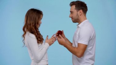 Erkek, mavi üzerine izole edilmiş kız arkadaşına evlenme teklif ediyor.