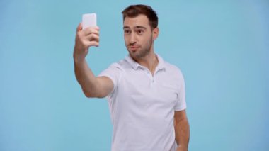 Gülümseyen adam mavi üzerine selfie çekiyor. 