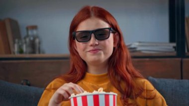 Neşeli genç kız televizyon izliyor ve patlamış mısır yiyor.