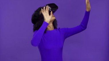 VR kulaklıklı meraklı Afrikalı Amerikalı kadın mor renkte izole edilmiş. 