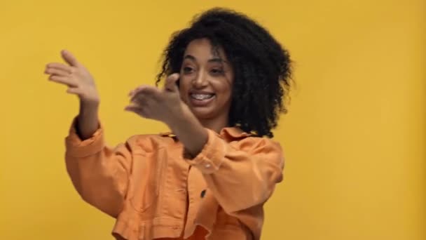Χαμογελαστή Αφροαμερικανή Γυναίκα Που Δείχνει Χέρια Απομονωμένα Στο Κίτρινο — Αρχείο Βίντεο