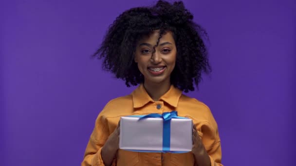 Souriant Afro Américaine Femme Tenant Cadeau Isolé Sur Violet — Video