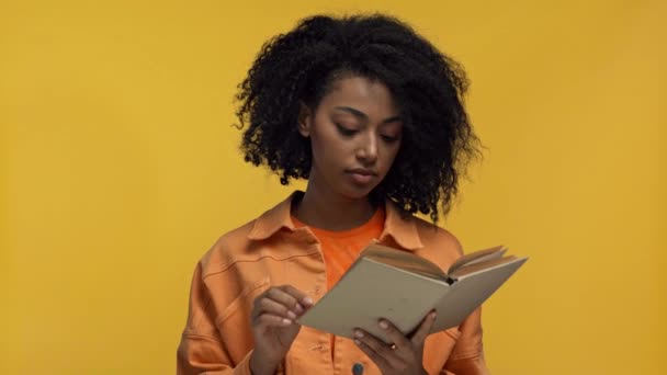 疲れたアフリカ系アメリカ人女性が黄色で隔絶された本を読んで — ストック動画