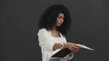 Siyahlara izole edilmiş kağıtlara yazan ciddi bir çift ırklı iş kadını.