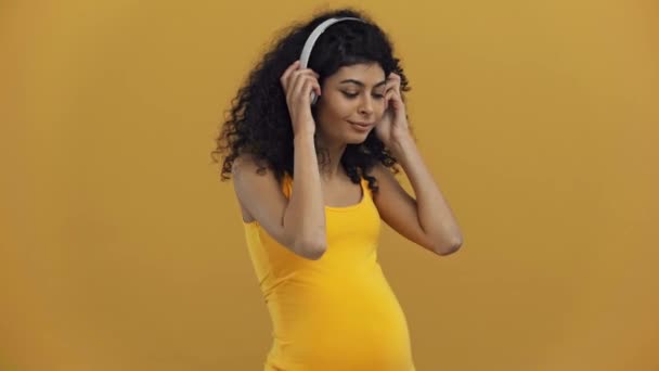 Glückliche Schwangere Frau Mit Kopfhörern Bauchnähe Isoliert Auf Dunkelgelb — Stockvideo