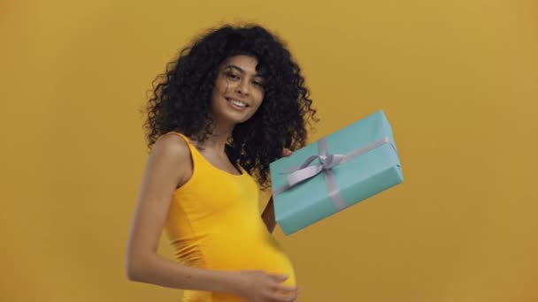 Feliz Racial Mujer Embarazada Mostrando Caja Regalo Aislado Amarillo Oscuro — Vídeos de Stock