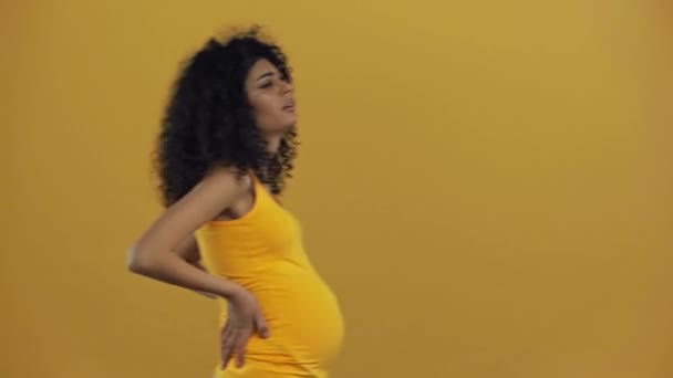 Unzufriedene Birassische Schwangere Berührt Bauch Isoliert Auf Dunkelgelb — Stockvideo