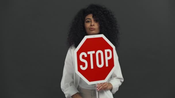 持怀疑态度的双种族妇女手持隔离在黑人身上的停止标语牌 — 图库视频影像