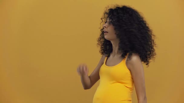 Fröhliche Birassische Schwangere Frau Zeigt Mit Dem Finger Auf Dunkelgelb — Stockvideo