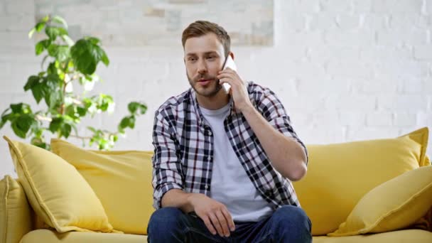 Hombre Alegre Sentado Sofá Hablando Teléfono Inteligente — Vídeos de Stock