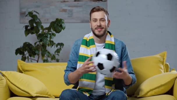 Glad Man Sitter Soffan Och Leker Med Fotboll — Stockvideo