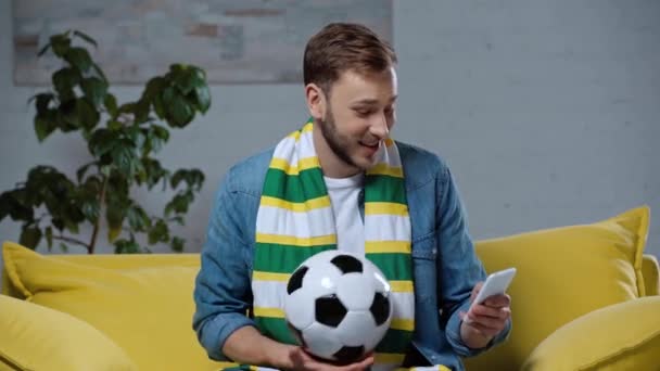 Uśmiechnięty Mężczyzna Gra Piłkę Nożną Podczas Dokonywania Zakładów Online — Wideo stockowe