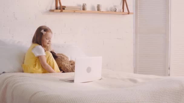 Дитина Дивиться Мультфільми Ноутбуці Поруч Плюшевим Ведмедем Ліжку — стокове відео