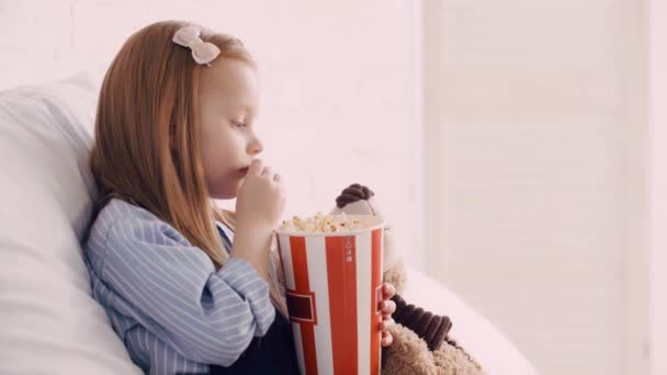 Niño Comiendo Palomitas Maíz Por Oso Peluche Viendo Dibujos Animados — Vídeo de stock