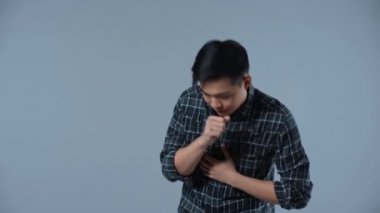 Hasta Asyalı adam gri üzerine öksürüyor. 