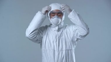 Asyalı bilim adamının koruyucu maskeyi çıkarması gri renkte izole edilmiş. 