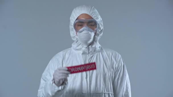 灰色に隔離されたコロナウイルスの文字が書かれた紙を指差すアジアの科学者 — ストック動画