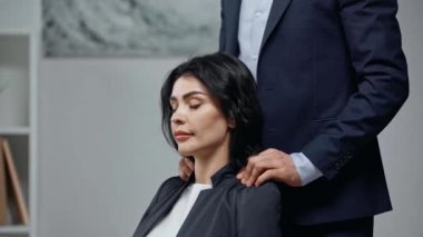 İş adamının çekici meslektaşına omuz masajı yapması.