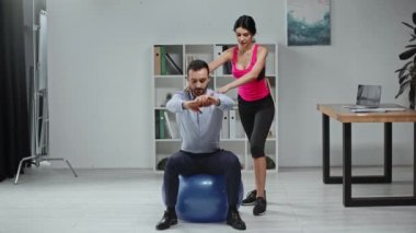 Genç antrenör, ofiste spor salonunda mekik çekmede iş adamına yardım ediyor.