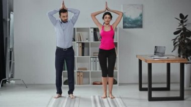 Güzel yoga eğitmeni ve yakışıklı iş adamı meditasyon pozları veriyor. 