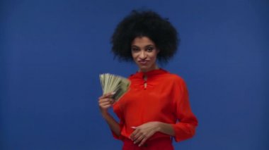 Mutlu Afro-Amerikalı kız mavi üzerine izole edilmiş havadan para atıyor.